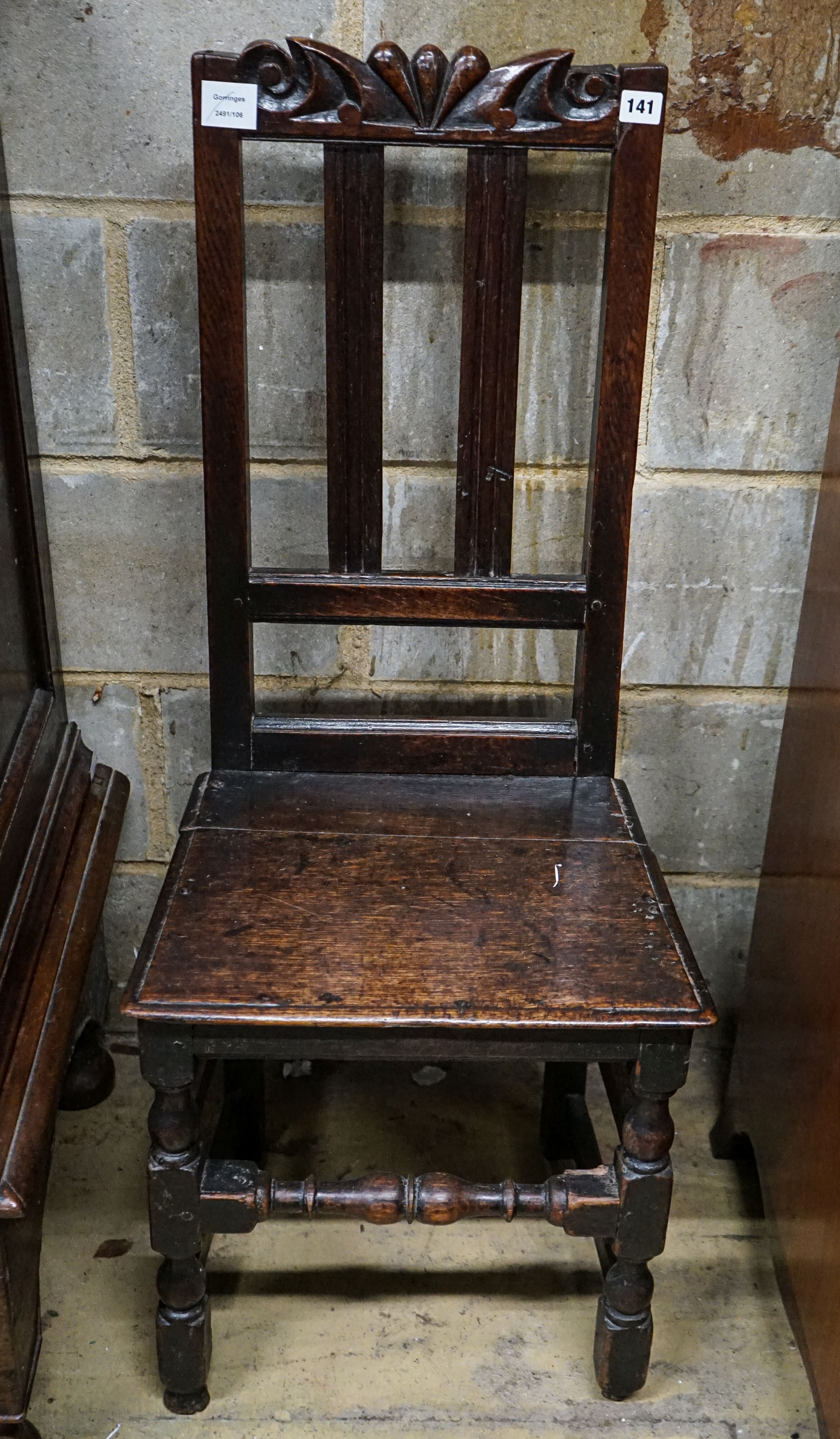 A late 17th century oak back stool, with carved cresting rail, slatted back and solid seat, on turned and square underframe, width 45cm, height 107cm